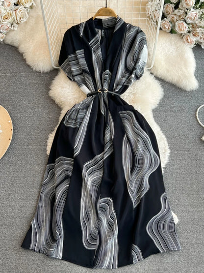 Vestido feminino midi de manga curta com decote em V, cintura marcada e modelagem evasê, da coleção de verão 2026 da Boutique Wholesale.