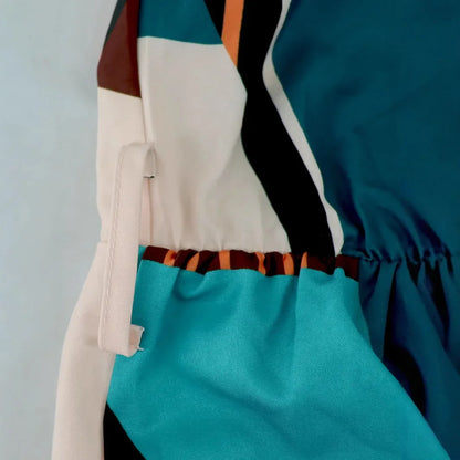Vestido longo boêmio de gola alta, sem mangas, tamanho grande, com estampa geométrica e blocos de cores. Cintura alta com amarração e comprimento até o tornozelo.