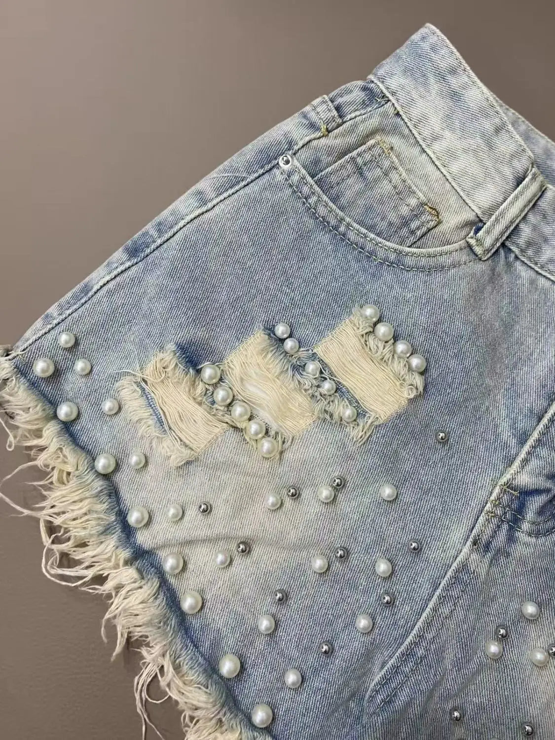 Shorts jeans femininos de verão com barra desfiada e detalhes em miçangas, modelo coreano, cintura alta, pernas largas e modelagem solta. Calça jeans curta e confortável.