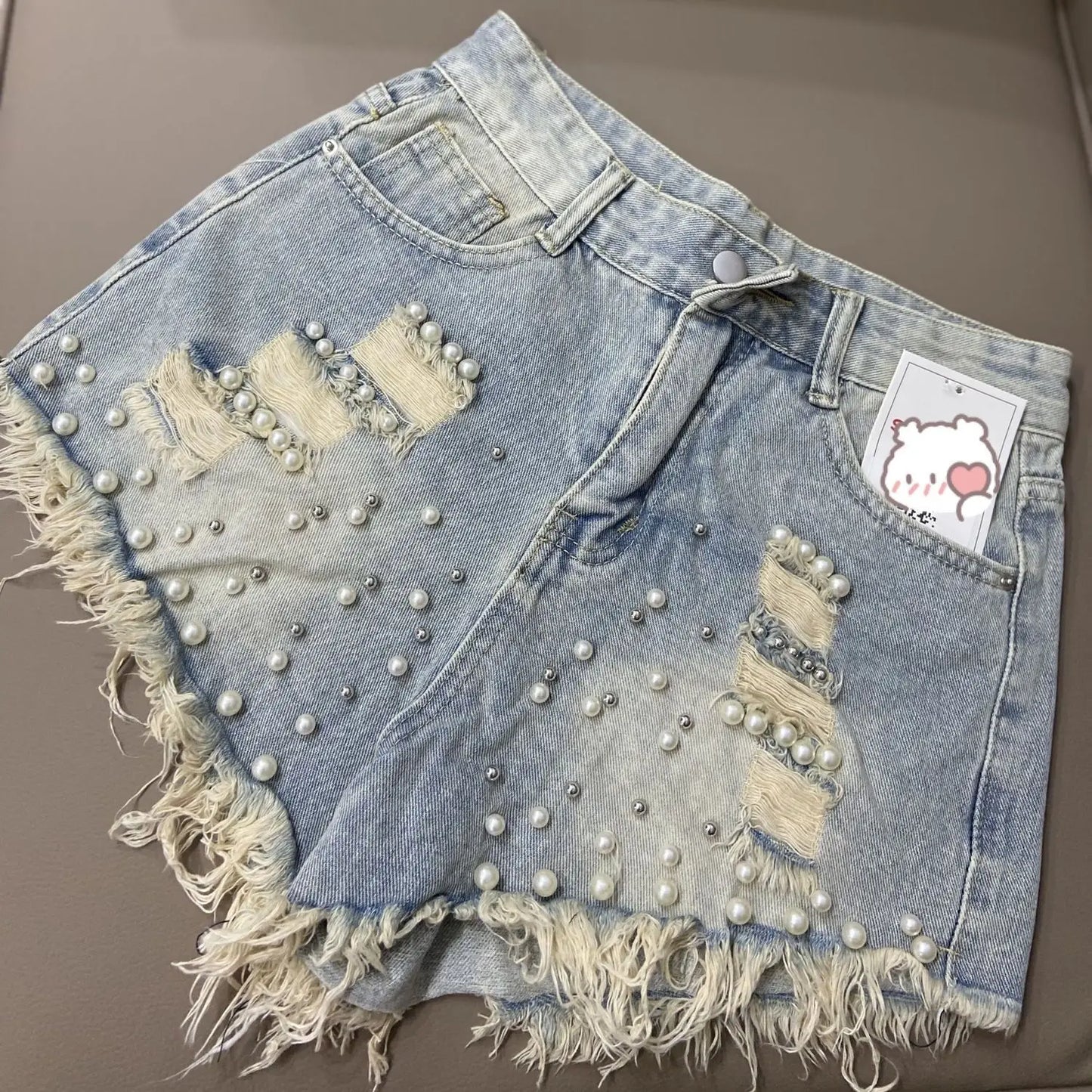 Shorts jeans femininos de verão com barra desfiada e detalhes em miçangas, modelo coreano, cintura alta, pernas largas e modelagem solta. Calça jeans curta e confortável.
