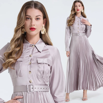 Vestido camisa feminino elegante, liso e plissado, com gola dobrável, mangas compridas, abotoamento simples e detalhe em viés. Acompanha cinto.
